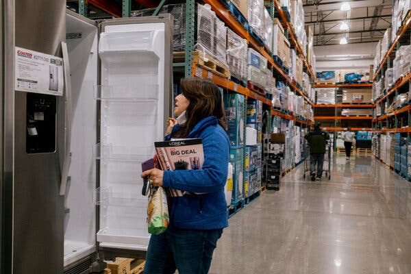 Una compradora abre la puerta de un frigorífico en un amplio pasillo de Costco.