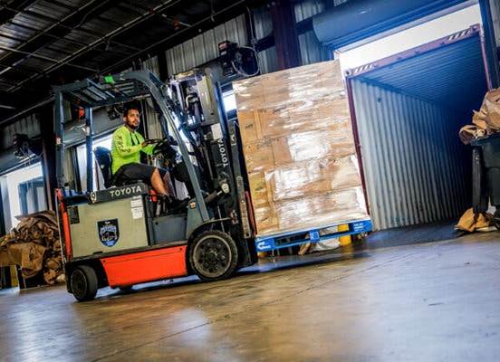 Una carretilla elevadora transportando cajas por un almacén.